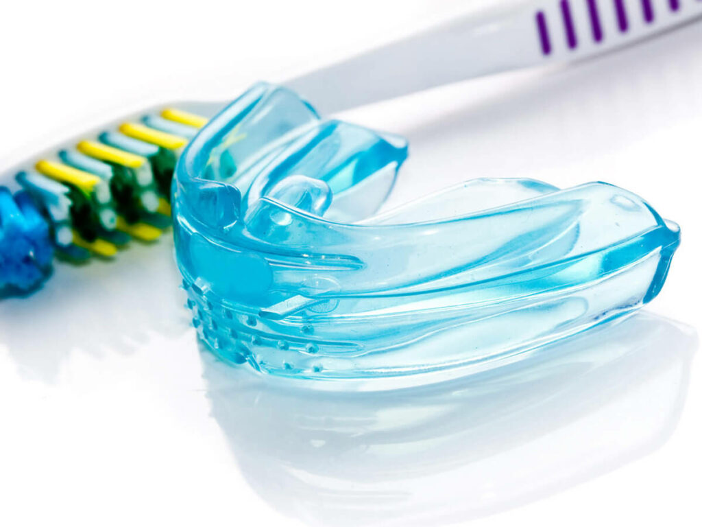 picture of blue mouth guard laying next to toothbrush