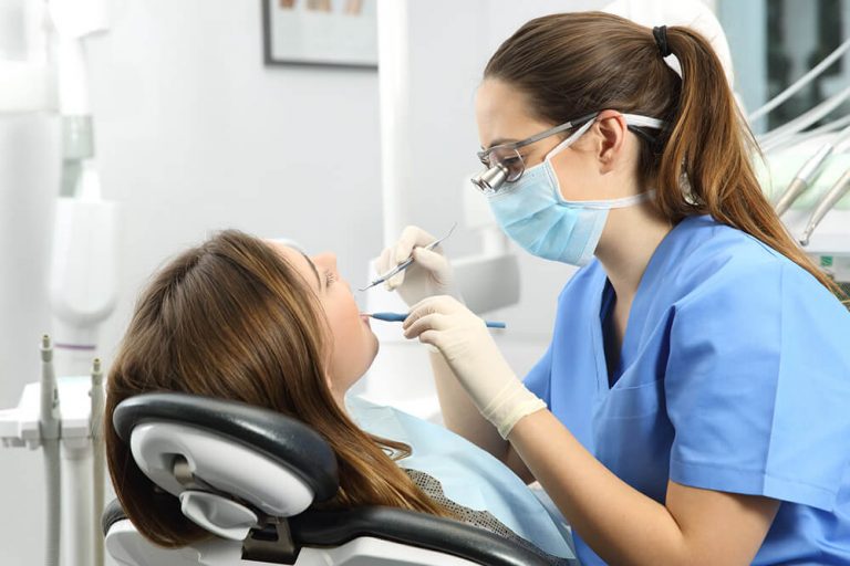 A dental hygienist performs a dental checkup and cleaning on a patient